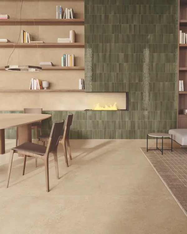 Haardwand met glanzende olijfgroene tegels, houten meubels en open planken boven een zandkleurige vloer.