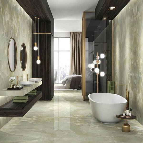 Badkamer met groene marmerlooktegels, een wit vrijstaand bad, donkere houttinten en goudkleurige accenten.