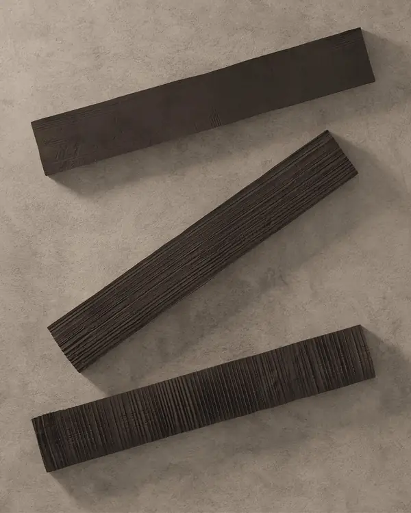 Kore-tegels: drie donkerbruine, langwerpige stalen met verschillend reliëf op een lichte ondergrond bij Kronos Ceramiche
