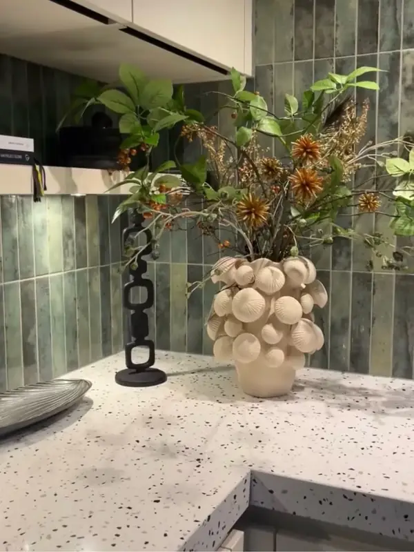 Groene keukenwandtegels in verticale plaatsing boven een gespikkeld werkblad bij Ras Badkamers & Vloeren