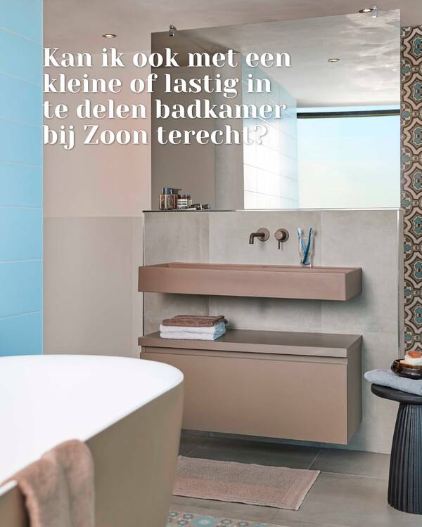 Badkamer met roze wastafel, zwevend opbergmeubel, grote spiegel, blauwe tegels en een decoratief tegelpatroon.